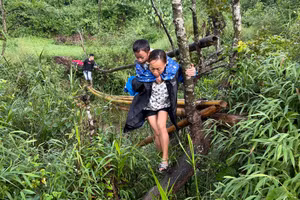 Cô giáo ở điểm Trường PTDT Bán trú Tiểu học Ái Quốc cõng học sinh đi qua suối. 