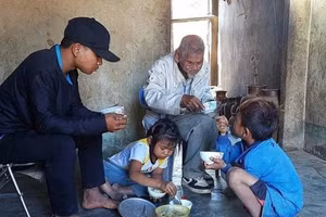 A Lương (bên trái) cùng 2 em và ông nội trong bữa cơm đạm bạc. Ảnh: Trúc Hân