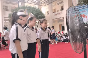 Học sinh tận hưởng luồng gió mát từ quạt công suất lớn lắp ở sân Trường Tiểu học Quang Trung. Ảnh: TG