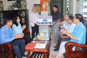 PGS.TS Lương Minh Cừ, Bí thư Đảng ủy, Hiệu trưởng Trường ĐH Cửu Long (bên trái) trao số tiền hỗ trợ gia đình anh Nguyễn Minh Trường.