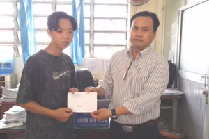 Thầy Huỳnh Bửu Tuấn, Hiệu trưởng Trường THPT Vĩnh Hải trao số tiền từ bạn đọc Báo GD&TĐ giúp đỡ cho em Lê Quốc Phi.