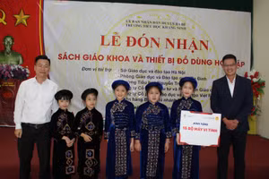 Ông Lê Đức Thuận - Trưởng phòng GD&ĐT quận Ba Đình (bên trái) cùng nhà tài trợ trao sách giáo khoa cho học sinh.