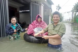 Người dân dùng phao tắm biển làm phương tiện vận chuyển trong nước lũ để đưa cụ bà đến Bệnh viện điều trị.