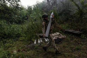 Một binh sĩ Ukraine mang theo một quả đạn pháo. (Ảnh: Getty Images)