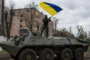 Binh sĩ Ukraine vẫy quốc kỳ khi đứng trên nóc xe bọc thép chở quân (APC). )Ảnh: Alexey Furman / Getty Images)