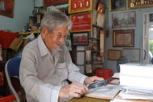 Nhà nghiên cứu Nguyễn Đình Tư dùng kính lúp, xem tài liệu tại nhà riêng. Ảnh: Mạnh Tùng