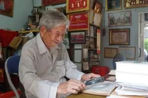 Nhà nghiên cứu Nguyễn Đình Tư dùng kính lúp, xem tài liệu tại nhà riêng. Ảnh: Mạnh Tùng