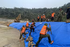 Lực lượng chức năng dùng bạt phủ lên đê để tránh bị nước làm xói mòn.