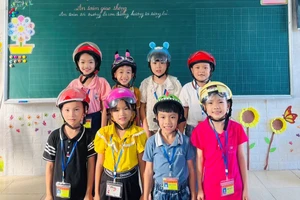 Học sinh lớp 2 thực hành đội mũ bảo hiểm an toàn, theo đúng quy định.