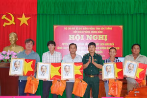 Thiếu tá Nguyễn Thanh Phong, đồn trưởng đồn Biên phòng Trung Bình tặng cờ Tổ quốc và ảnh Bác Hồ cho các chủ phương tiện.