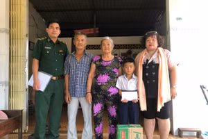 Đại diện đồn Biên phòng Côn Đảo và Công ty Bất động sản Elly Nguyễn trao quyết định nhận đỡ đầu và tặng quà cho em Nguyễn Hoàng Phi.