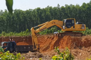 Máy xúc hoạt động liên tục để lấy đất chất lên xe tải chở ra ngoài.