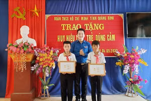 Đại diện Tỉnh Đoàn Quảng Bình trao Huy hiệu "Tuổi trẻ dũng cảm" của Trung ương Đoàn cho hai học sinh. 