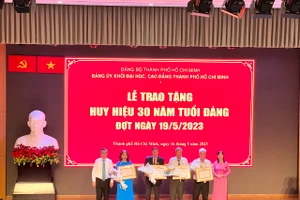 Bà Nguyễn Thị Là, Phó Bí thư Thường trực Đảng ủy Khối Đại học, Cao đẳng TPHCM (bìa phải) trao tặng Huy hiệu 30 năm tuổi Đảng cho các đảng viên. 