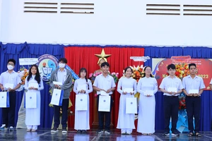 PGS.TS Vũ Văn Nhiêm (trái)- Chủ tịch Hội đồng Trường ĐH Luật TPHCM trao học bổng cho học sinh đặc biệt xuất sắc. 