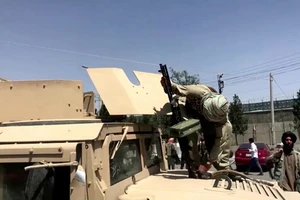 Một chiến binh Taliban nạp lại súng máy của mình trên chiếc xe bọc thép Humvee do Mỹ sản xuất mà họ giành được ở Kabul, Afghanistan. 