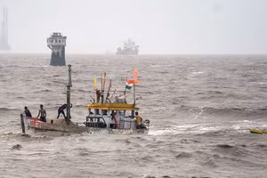 Ngư dân trên một chiếc thuyền đánh cá cố gắng vớt chiếc thuyền nhỏ hơn của họ đã trôi đi do biển động do cơn bão Tauktae 