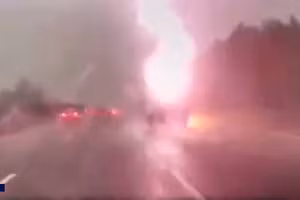 Hình ảnh sét đánh gần một chiếc xe hơi sắp chạy qua.