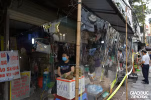 Tiểu thương bán hàng sau lớp tấm chắn bằng nilong.