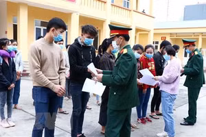 Cán bộ Bộ Chỉ huy Quân sự và Sở Y tế tỉnh Hòa Bình trao giấy chứng nhận hoàn thành thời gian cách ly y tế tập trung cho sinh viên Lào. (Ảnh: Thanh Hải/TTXVN).