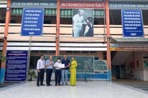 Anh Nguyễn Đặng Thanh Minh và con trai Nguyễn Tấn Đạt, nhận khoản hỗ trợ tình nghĩa từ Ban Giám hiệu Trường tiểu học Bình Chiểu, sáng 11/4 vừa qua.