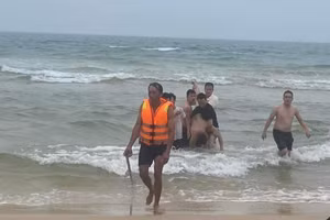 Lực lượng cứu hộ cùng người dân đưa nạn nhân vào bờ.