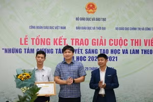 Ông Doãn Hồng Hà (ở giữa) chúc mừng tác giả Trần Tuấn Ngọc (ngoài cùng bên phải) và trao phần thưởng cho thầy giáo Vũ Xuân Quế - Hiệu trưởng Trường THCS và THPT Bát Xát (Lào Cai) - nhân vật trong tác phẩm “Người thầy mang bếp lửa đến vùng cao”.