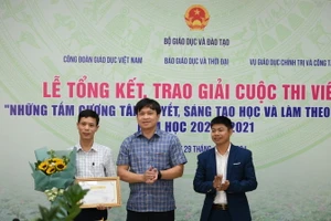 Ông Doãn Hồng Hà (ở giữa) chúc mừng tác giả Trần Tuấn Ngọc (ngoài cùng bên phải) và trao phần thưởng cho thầy giáo Vũ Xuân Quế - Hiệu trưởng Trường THCS và THPT Bát Xát (Lào Cai) - nhân vật trong tác phẩm “Người thầy mang bếp lửa đến vùng cao”.