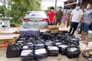 Nguyễn Văn Thắng (áo đỏ) cùng tang vật là 7.800 bao thuốc lá lậu. Ảnh: Công an An Giang.