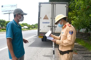 Lực lượng CSGT tại chốt kiểm tra y tế khu vực cầu Cỏ May (phường 12, TP. Vũng Tàu) kiểm tra giấy xét nghiệm âm tính COVID-19 một tài xế xe tải khi phương tiện qua chốt. Ảnh: Sa Huỳnh.