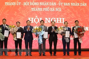 Bí thư Thành ủy Vương Đình Huệ và Chủ tịch UBND thành phố Chu Ngọc Anh trao quyết định và tặng hoa chúc mừng năm tân Phó Chủ tịch UBND thành phố Hà Nội. (Ảnh: Văn Điệp/TTXVN).