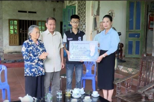 Bà Nguyễn Kim Chi - Bí thư Huyện ủy, Chủ tịch HĐND huyện Thanh Ba trao biểu trưng "Mẹ đỡ đầu" hỗ trợ cho em Mai Thanh Bình. Ảnh: Hải Minh