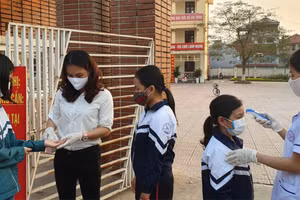 Nhân viên y tế đo thân nhiệt cho học sinh tại cổng Trường Tiểu học Liên Bảo. Ảnh tư liệu