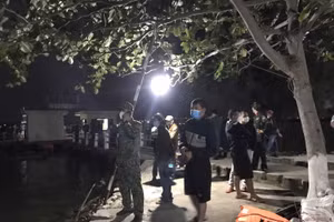 Nhiều người đang đứng trên bờ chờ thông tin người thân.