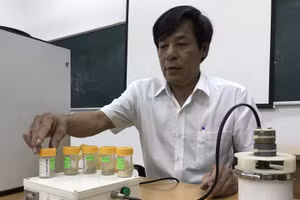 Thầy Nguyễn Văn Thịnh với chiếc máy nghiền bi trục đứng do mình chế tạo. 