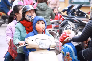 Học sinh Hà Nội được bố mẹ đưa đến lớp trong ngày trời rét. 