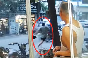 Chủ quán (khoanh đỏ) đuổi theo nam thanh niên mua thẻ điện thoại nhưng không trả tiền. Ảnh cắt từ clip. 