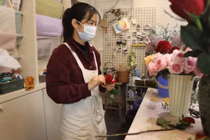 Chị Đinh Hồng Ngọc - Quản lý shop hoa trên phố Nguyễn Cao, Hà Nội giới thiệu với khách mua hoa.