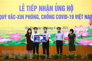 Thứ trưởng Bộ Lao động, Thương binh và Xã hội Lê Tấn Dũng (giữa) trao ủng hộ Quỹ cho Phó Tổng giám đốc Kho bạc Nhà nước Nguyễn Quang Vinh. (Ảnh: Hoàng Hiếu/TTXVN).