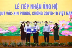 Thứ trưởng Bộ Lao động, Thương binh và Xã hội Lê Tấn Dũng (giữa) trao ủng hộ Quỹ cho Phó Tổng giám đốc Kho bạc Nhà nước Nguyễn Quang Vinh. (Ảnh: Hoàng Hiếu/TTXVN).