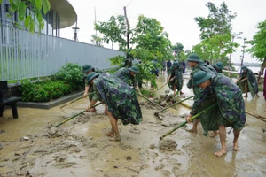 Các chiến sĩ mặc áo mưa dọn dẹp bùn đất.