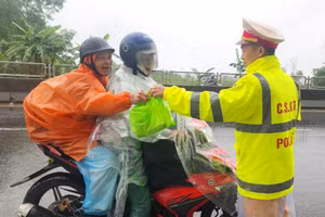 Các chiến sĩ Trạm CSGT Phú Lộc, Công an tỉnh thừa Thiên - Huế phát nước uống, thức ăn miễn phí cho người dân trên đường vào Nam làm việc trở lại sau Tết (Ảnh: T.H).