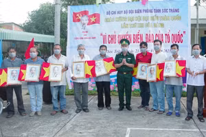 Đại tá Lê Văn Anh, Phó Chính uỷ, BĐBP tỉnh trao cờ Tổ quốc và ảnh Bác Hồ cho ngư dân.