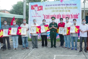 Đại tá Lê Văn Anh, Phó Chính uỷ, BĐBP tỉnh trao cờ Tổ quốc và ảnh Bác Hồ cho ngư dân.