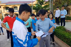 Thầy Tập (bên phải) phát thẻ dự thi kì thi chọn học sinh giỏi cấp tỉnh cho các em học sinh. Ảnh: NVCC