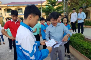 Thầy Tập (bên phải) phát thẻ dự thi kì thi chọn học sinh giỏi cấp tỉnh cho các em học sinh. Ảnh: NVCC