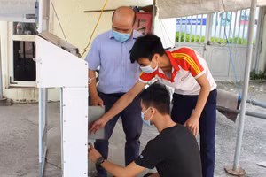 PGS.TS Phạm Thành Long cùng nhóm sinh viên Trường Đại học Kỹ thuật Công nghiệp bên máy đo thân nhiệt và rửa tay tự động phòng dịch Covid-19.