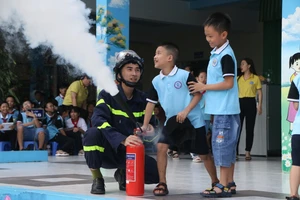 Học sinh Trường Tiểu học Trần Quốc Toản thực hành kĩ năng sử dụng bình chữa cháy mini. 