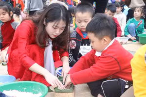 Cô giáo chỉ cho học sinh từng khâu để gói bánh chưng bằng khuôn. 