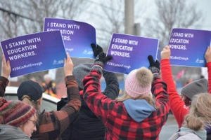 Đám đông cầm biểu ngữ 'I stand with education workers' (dịch: Tôi đứng về phía nhân viên giáo dục).